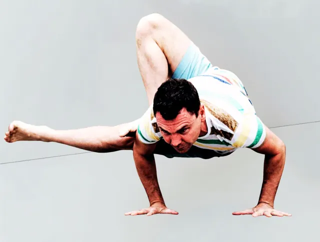 Leigh balancing on his hands in a yoga arm balance